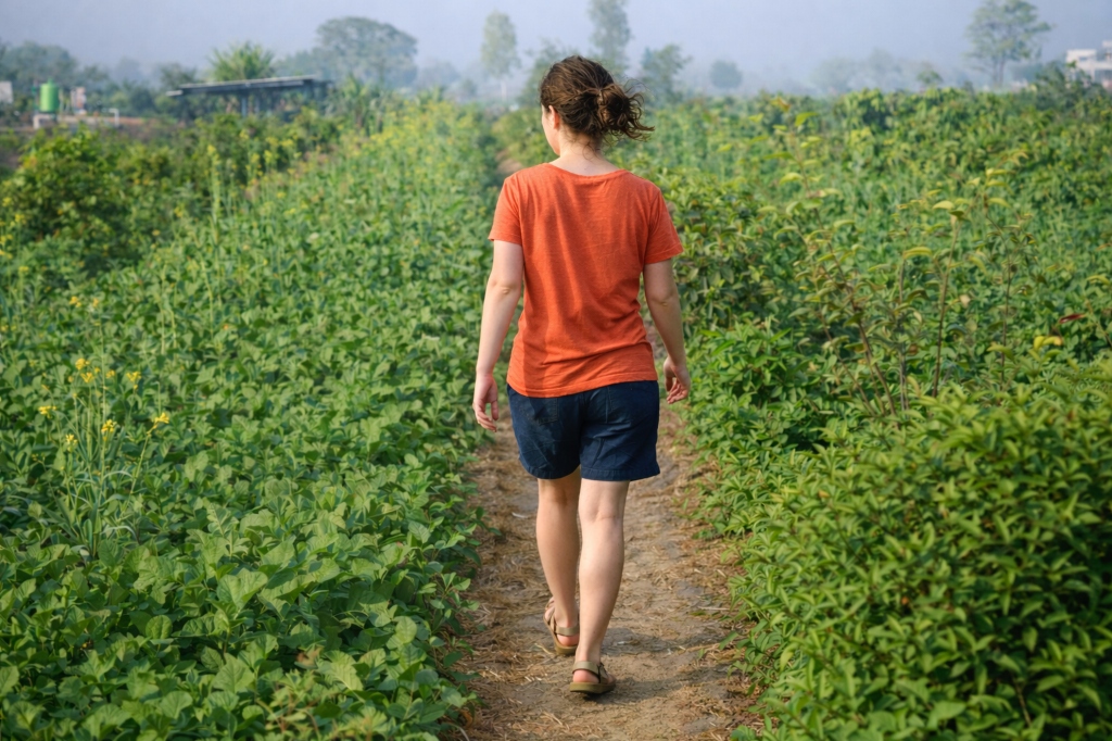 Woman walking away through lush green fields